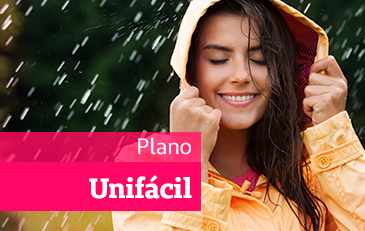 Foto de mulher jovem usando capa de chuva sorrindo na chuva com as mãos no capuz